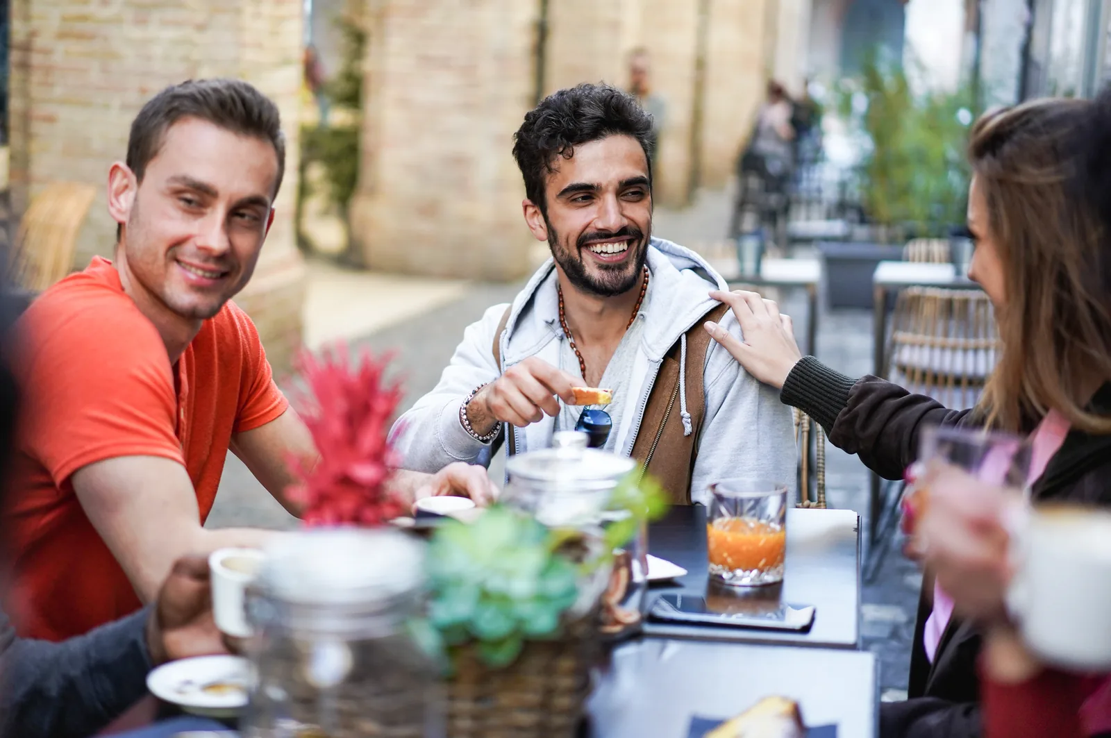 Friends smiling and chatting over brunch at an outdoor café