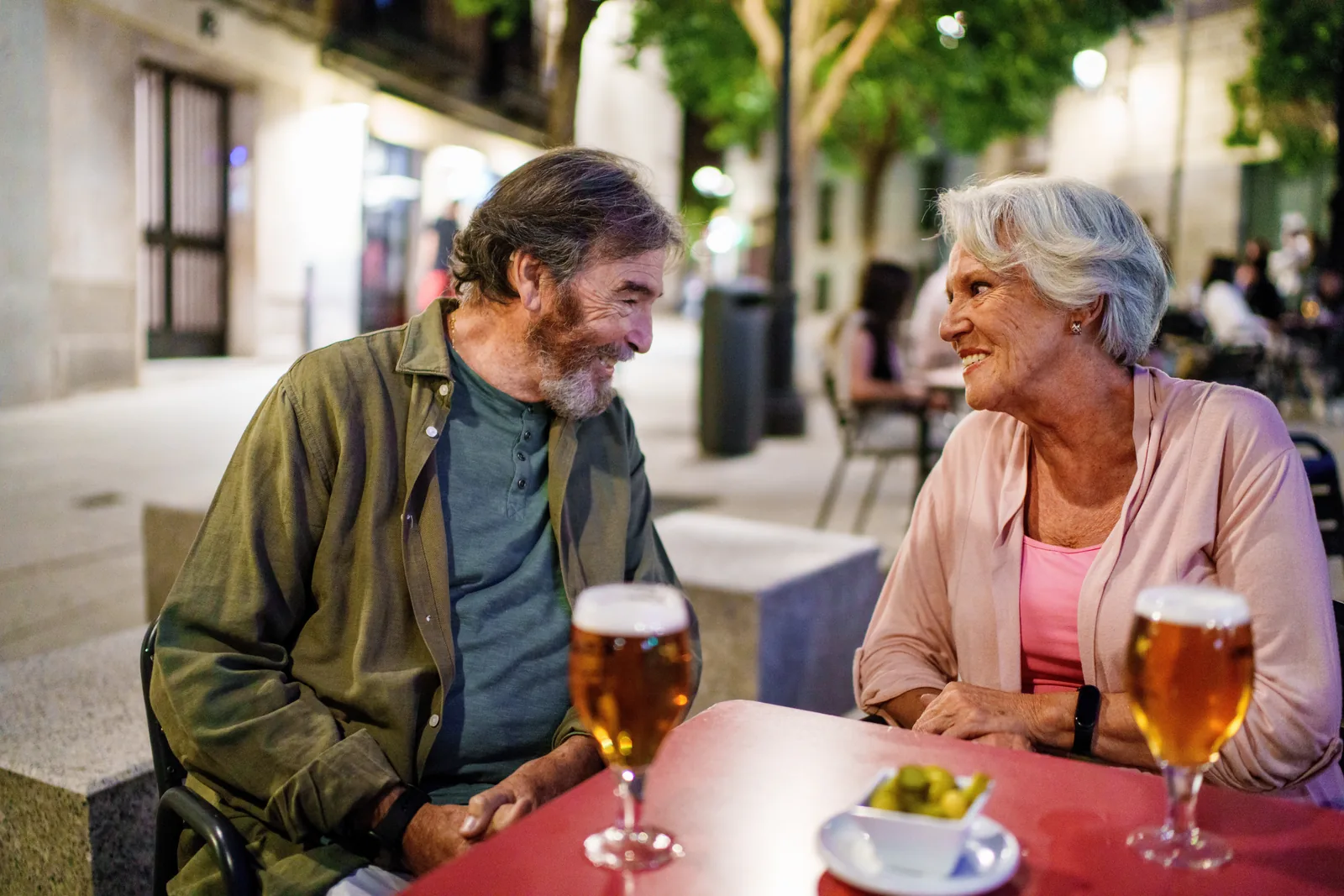Older couple smiling and enjoying drinks together at an outdoor café