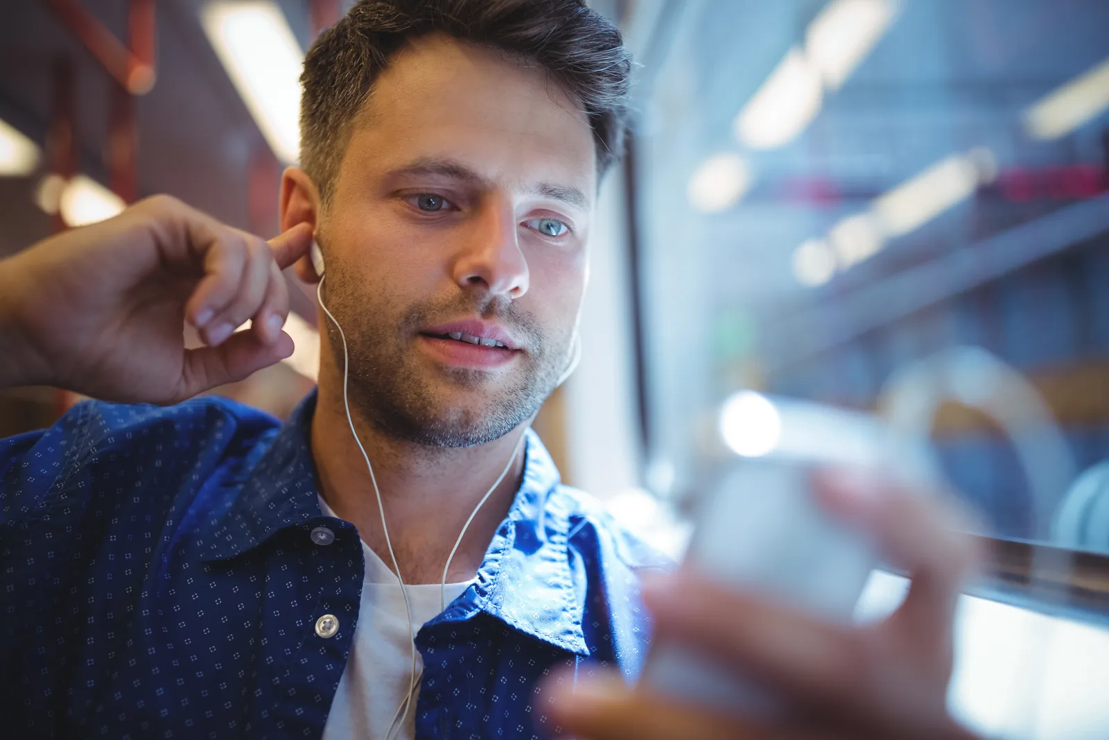 Man wearing earphones and using his phone while travelling on a train