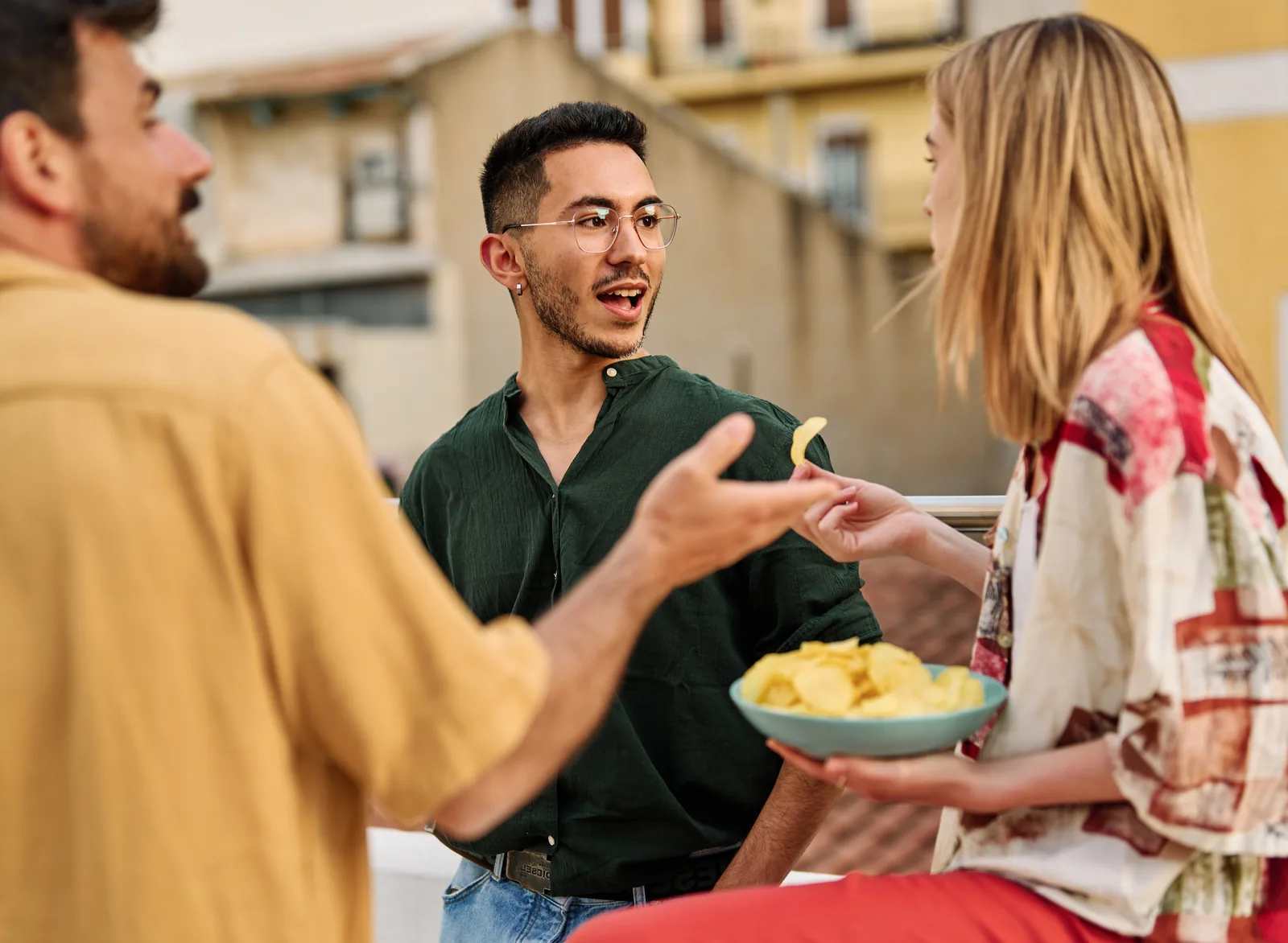 Friends chatting and sharing snacks on an urban rooftop patio