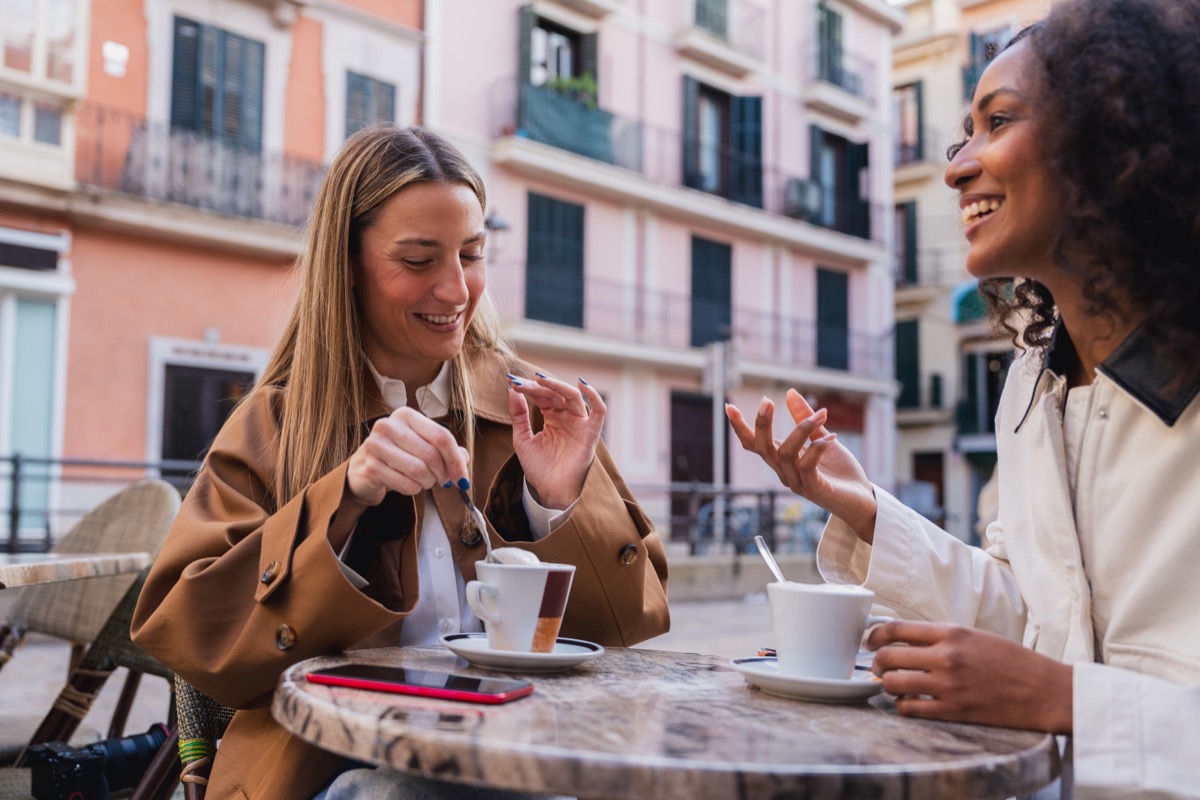 Two women chatting over coffee at an outdoor café